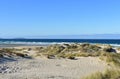 Wild beach with sand dunes and grass. Blue sea with waves and white foam, clear sky, sunny day. Galicia, Coruna Province, Spain. Royalty Free Stock Photo