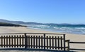 Beach with wooden boardwalk and handrail. Wild sea with waves and blue sky. Arteixo, Coruna, Galicia, Spain.