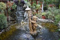 Artesian well with statues small waterfall and flowers . Royalty Free Stock Photo