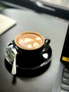 Artful Coffee Latte in a Black Cup on Office Desk