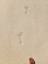 Artful human footprints with part of right foot in fine bright beige sandy beach