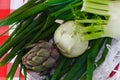 Artichoke, green onion, fenchel and kohlrabi in white wooden basket with straw