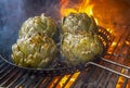 Artichokes charred in pan on BBQ with flames and smoke Royalty Free Stock Photo