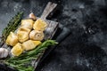 Artichokes hearts marinated with olive oil and herbs, pickled artichoke with garlic on wooden board. Black background