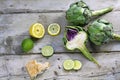 Artichokes whole and halved with lemons, limes and bread on weat Royalty Free Stock Photo