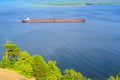 An articulated tugboat and barge bulk carrier transports sand and construction materials on the river. The large barge sails along