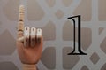 Articulated wooden hand with a finger raised in allusion to number one