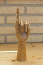 Articulated wooden hand making the sign of the one