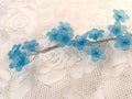 Close up cute artificial blue flowers on the white lace background Royalty Free Stock Photo