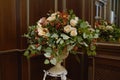 Artificial bouquet of flowers and berries in white antique vase near mirror.