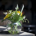 The Artificial bouquet of leaves of monstera Alismatales , gerbera Transvaal daisy and sunflower in the glass vase on the table