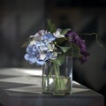 The artificial bouquet of pink and purple hydrangeas on a table in a cafe. The sun gives shadows