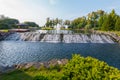 An artificial cascading waterfall flows from a lake in the park near a wooden gazebo with a terrace. Novi Petrivtsi