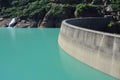 Artificial concrete dam, green mountain lake waters Royalty Free Stock Photo