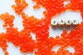 Artificial fake red caviar on a white surface next to the fake sign. The concept of unnatural food, counterfeiting and consumer Royalty Free Stock Photo