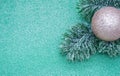 Artificial fir branch with golden shiny Christmas ball on a green glitter background. Copy space Royalty Free Stock Photo