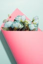Artificial flowers bouquet wrapped in pink paper on a light blue background.