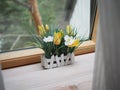 Artificial flowers in crafting pots on a wooden windowsill, ecodesign