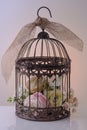 Artificial flowers in a decorative birdcage.