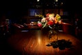 Artificial flowers in a glass bottle are placed on the wooden table with light from the orange lamp, look like the night of a