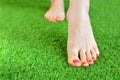 Tender female foots on a green artificial turf floor