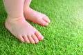 Artificial grass background. Tender foots of a baby on a green artificial turf. Royalty Free Stock Photo
