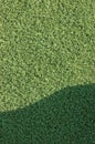 Artificial grass fake turf synthetic lawn field macro closeup with gentle shaded shadow area, green sports texture background Royalty Free Stock Photo