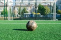 Artificial grass, white lines, soccer goal and an old shabby worn soccer ball in front of the goal on a sunny day Royalty Free Stock Photo