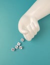 Artificial hand throwing dice on a teal background. Royalty Free Stock Photo