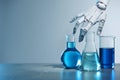 Artificial intelligence. Robot hand and laboratory glassware with liquids on table against light grey background, space for text Royalty Free Stock Photo