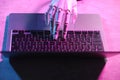 Artificial intelligence. Robot hand using laptop on table in neon lights, above view Royalty Free Stock Photo
