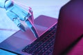 Artificial intelligence. Robot hand using laptop on table in neon lights, closeup Royalty Free Stock Photo