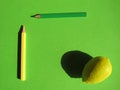 Artificial lemon and pencils on a green background