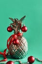 Artificial metal pineapple decorated with red balls, ribbon and golden garland