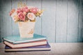 Artificial Rose in flower pot with pile of notebooks