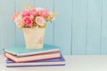 Artificial Rose in flower pot with pile of notebooks