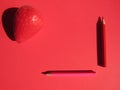 Artificial strawberry and pencils on a red background