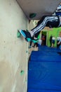 Rock climbing for children. Blond boy in a green shirt is climbing climbing wall. Bouldering class. Artificial track for safe Royalty Free Stock Photo