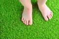 Artificial turf background. Tender foots of a baby on a green artificial grass floor. Royalty Free Stock Photo