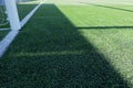 Artificial turf on football soccer field. Part of soccer goal and green synthetic grass on sport ground with shadow from Royalty Free Stock Photo