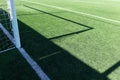 Artificial turf on football soccer field. Part of soccer goal and green synthetic grass on sport ground with shadow from Royalty Free Stock Photo