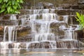 Artificial water fall in the garden. artificial pond with a waterfall in a landscape design. A small artificial waterfall surround Royalty Free Stock Photo