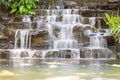 Artificial water fall in the garden. artificial pond with a waterfall in a landscape design. A small artificial waterfall surround Royalty Free Stock Photo