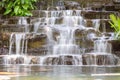 Artificial water fall in the garden. artificial pond with a waterfall in a landscape design. A small artificial waterfall surround Royalty Free Stock Photo