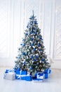 Artificial white christmas tree on white, decorated with blue ornaments and garland, Modern Christmas interior. Royalty Free Stock Photo