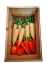 The artificial white radish, capsicum and carrot which is made of plastic, displaying on brown straw in a wooden box.