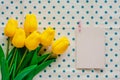 Artificial yellow tulips with white paper card on blue polka dot