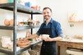 Artisan Holding Clay Bowl By Shelves In Pottery Workshop