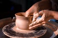 Potter master woman sculptor works with clay on a Potter& x27;s wheel and at the table with the tools. Close-up.