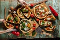 Artisan pizzas on old painted wood with hands Royalty Free Stock Photo